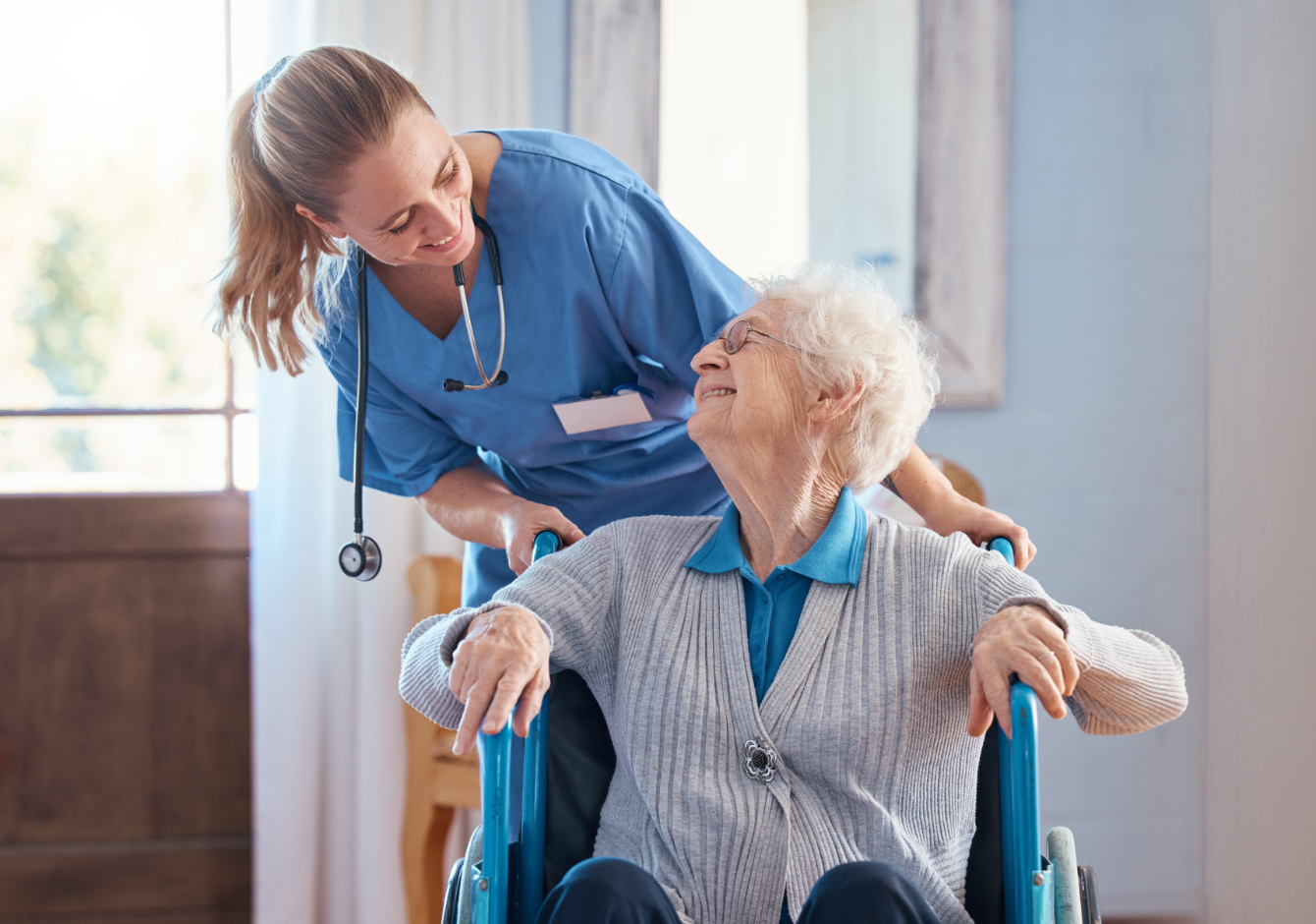 A nurse smiling and caring for an elderly woman in a wheelchair at home — in-home aged care across the ACT.